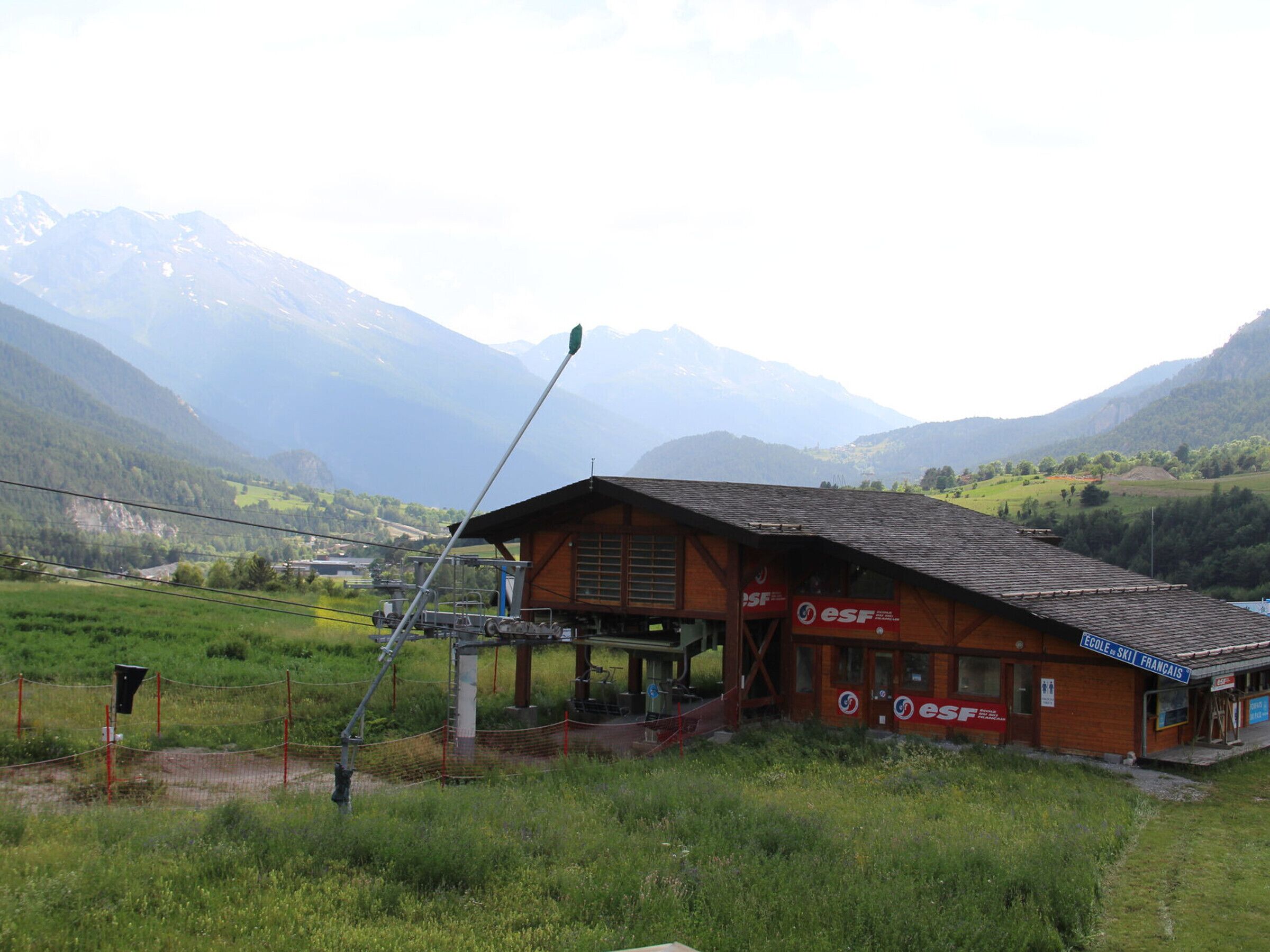 A wooden building with a sloped roof, labeled "ESF," in a rural setting with mountains in the background.