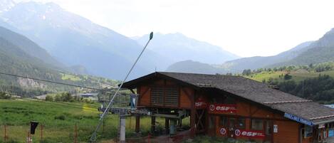 A wooden building with a sloped roof, labeled "ESF," in a rural setting with mountains in the background.