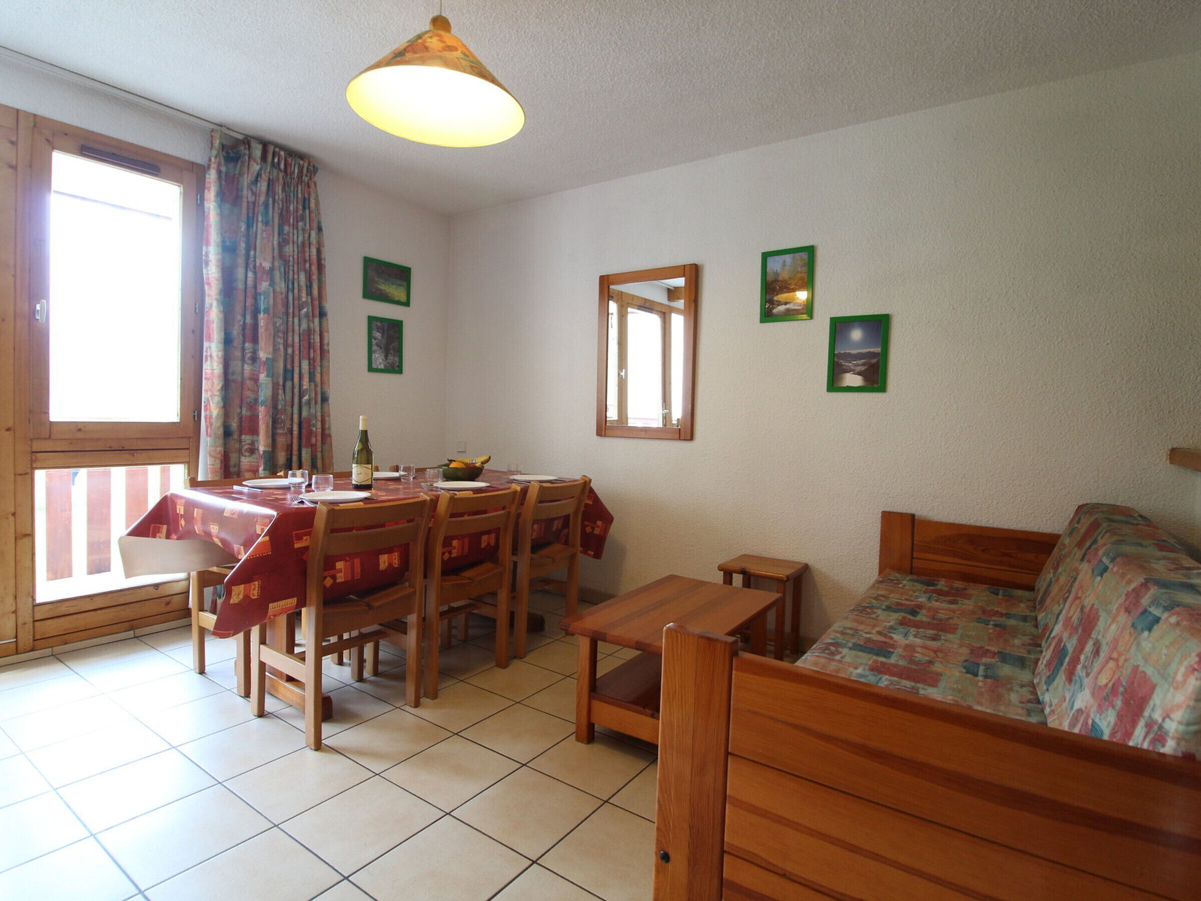 Una habitación acogedora con una mesa de comedor preparada para dos personas, un sofá de madera y una pequeña mesa de madera.