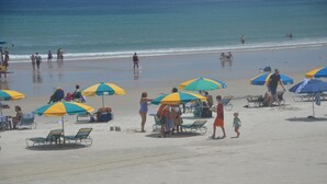 Una playa con varios sombrillas coloridas y sillas de playa.