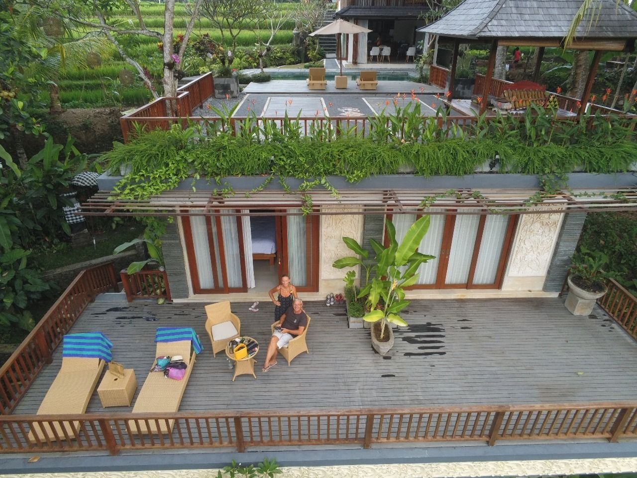 A rooftop terrace with lounge chairs, a dining area, and a view of the surrounding greenery.