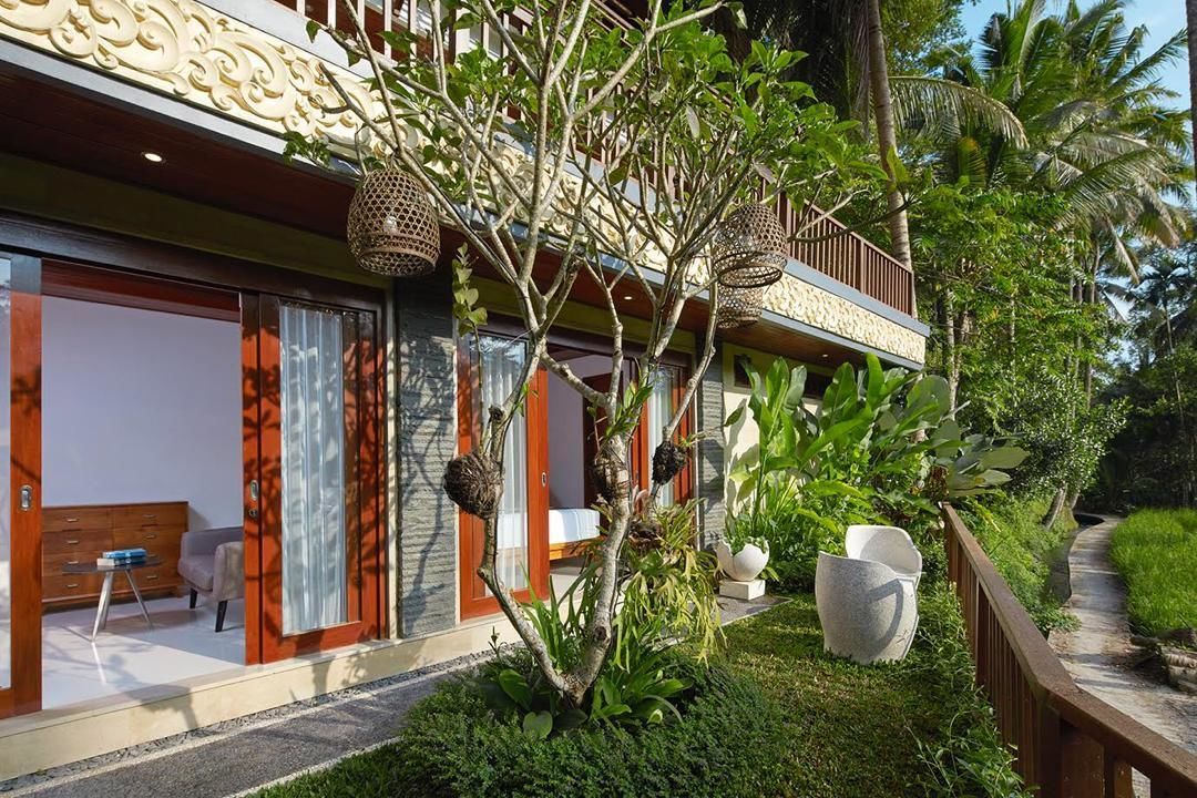 A modern building with a balcony, a small garden, and a pathway.