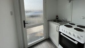 A compact kitchen with a white stove, sink, and a frosted glass door. - The Ship Inn (Gloucester)