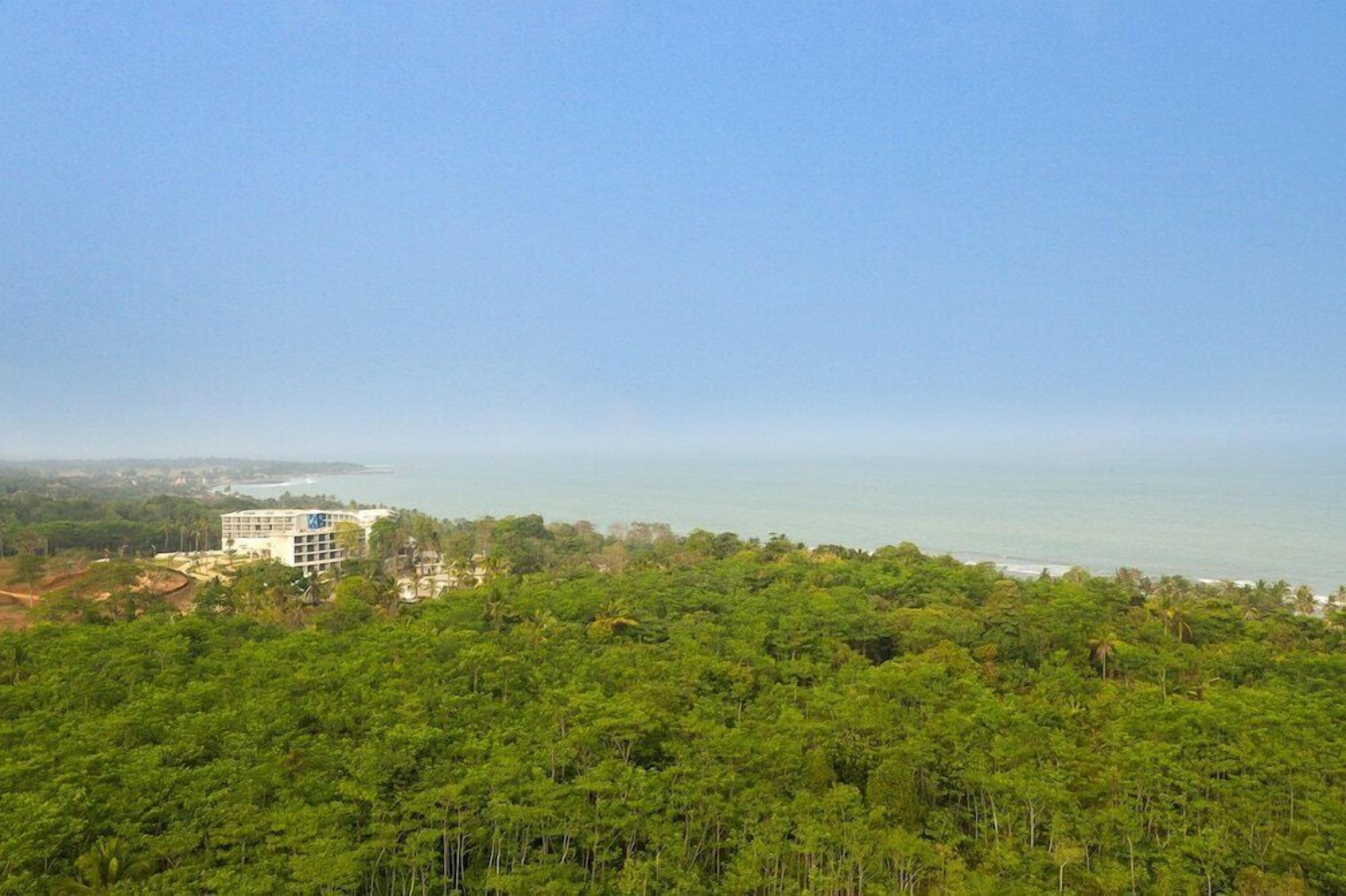 A hotel with a view of the ocean and dense forest.