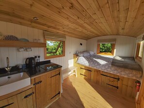 Una cabaña pequeña con kitchenette, una cama y ventana con vista a la vegetación.