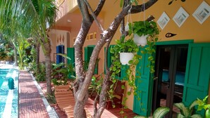 A poolside area with a tiled floor, wooden lounge chairs, and potted plants. - MiNhon Hotel Mui Ne (Mui Ne)