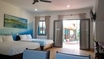 A hotel room with two beds, a ceiling fan, a painting, and a view of the outdoor area.