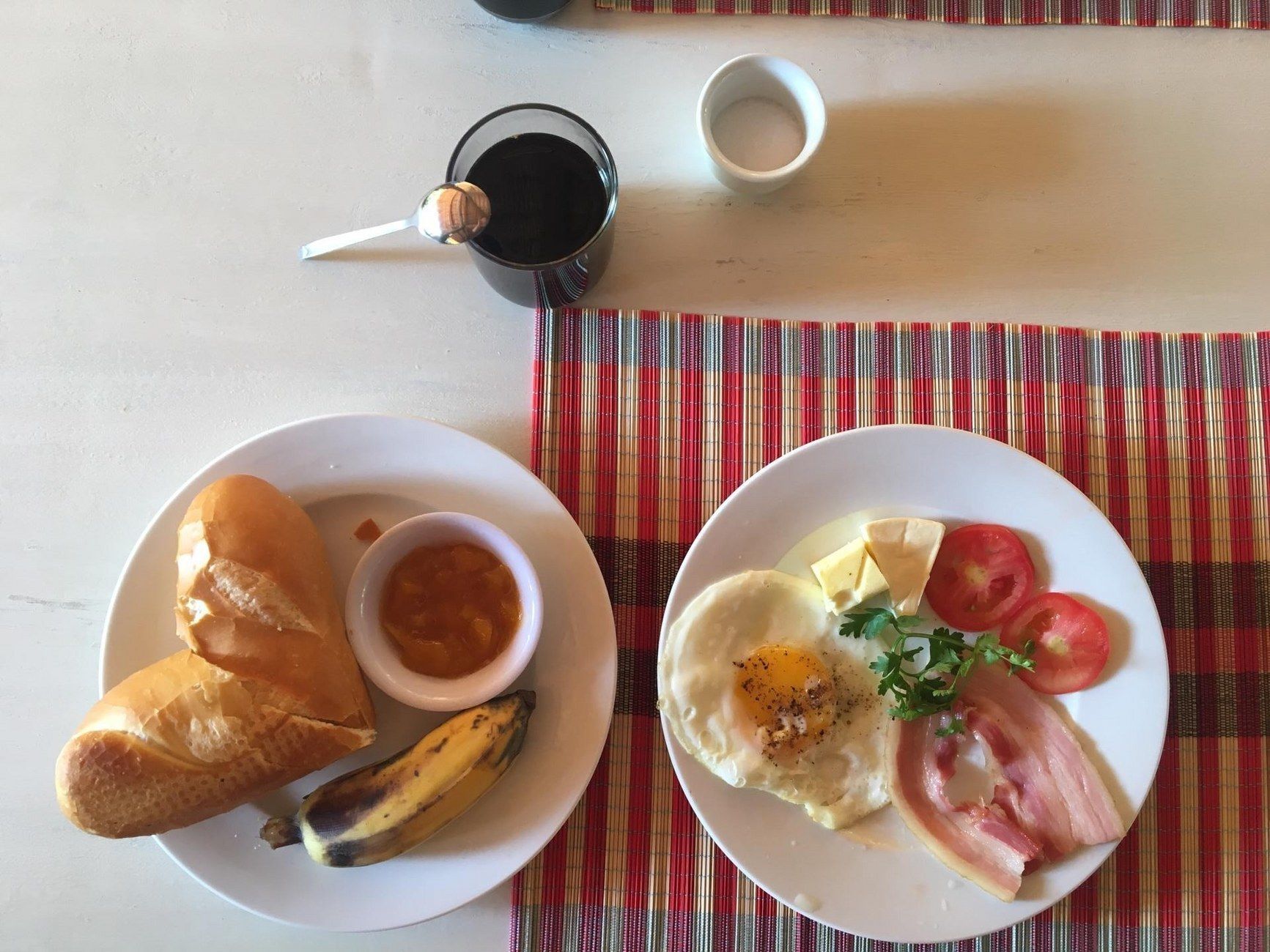 Un plato de desayuno con tostadas, un plátano y un tazón pequeño de mermelada.