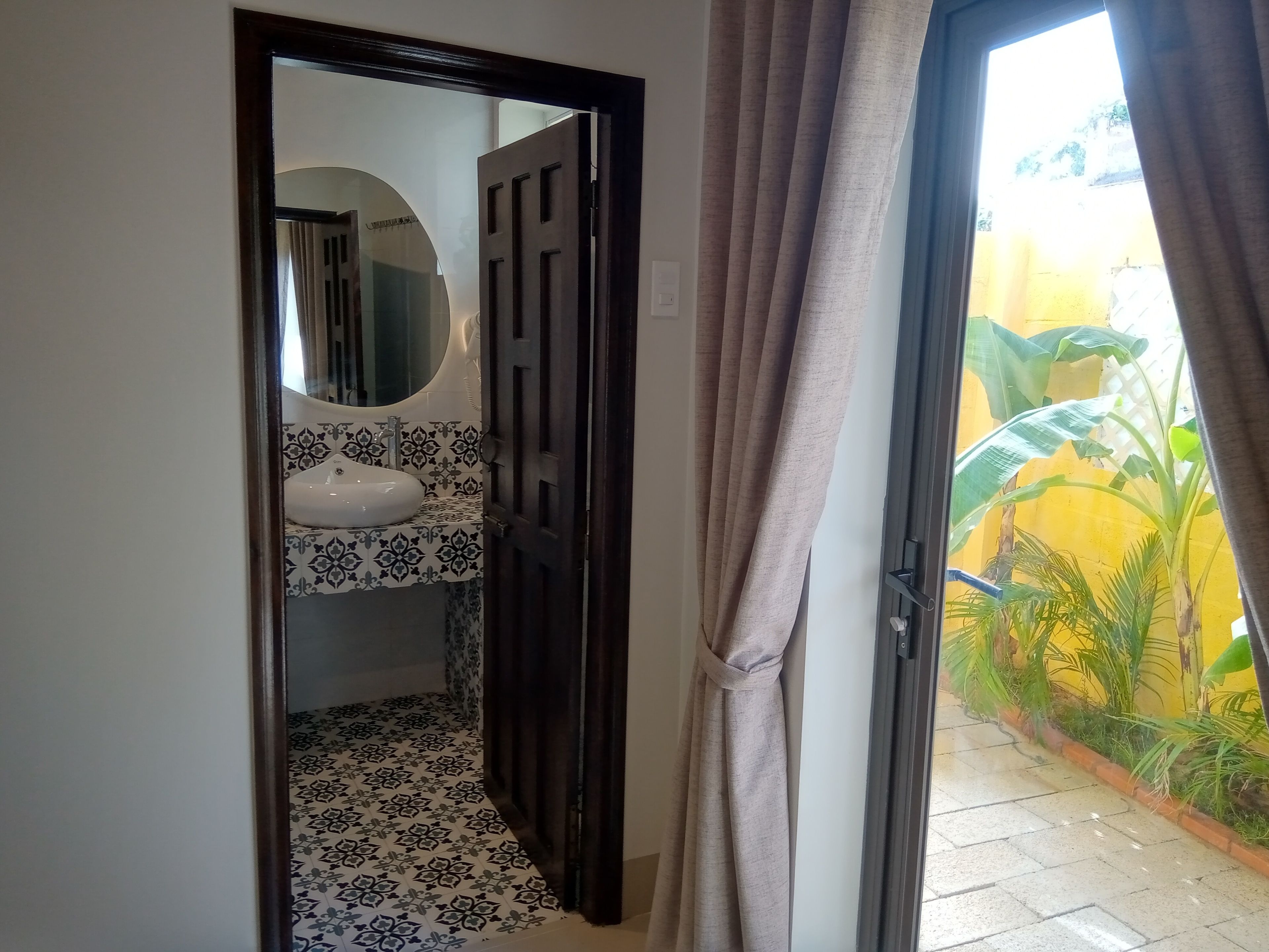 Un baño con un lavamanos blanco, baldosas estampadas y un espejo.