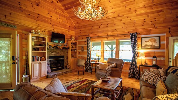Een gezellig chalet interieur met een open haard, houten wanden, een televisie en een comfortabele zithoek.