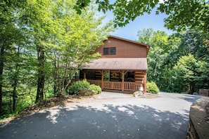 A two-story log cabin with a porch and a stone fireplace.