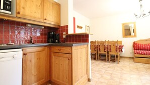 A kitchen with wooden cabinets, a microwave, a coffee maker, and a dining area with a table and chairs. - Spacious apartment for 6 people at the foot of the slopes with parking and WIFI (Lanslevillard)