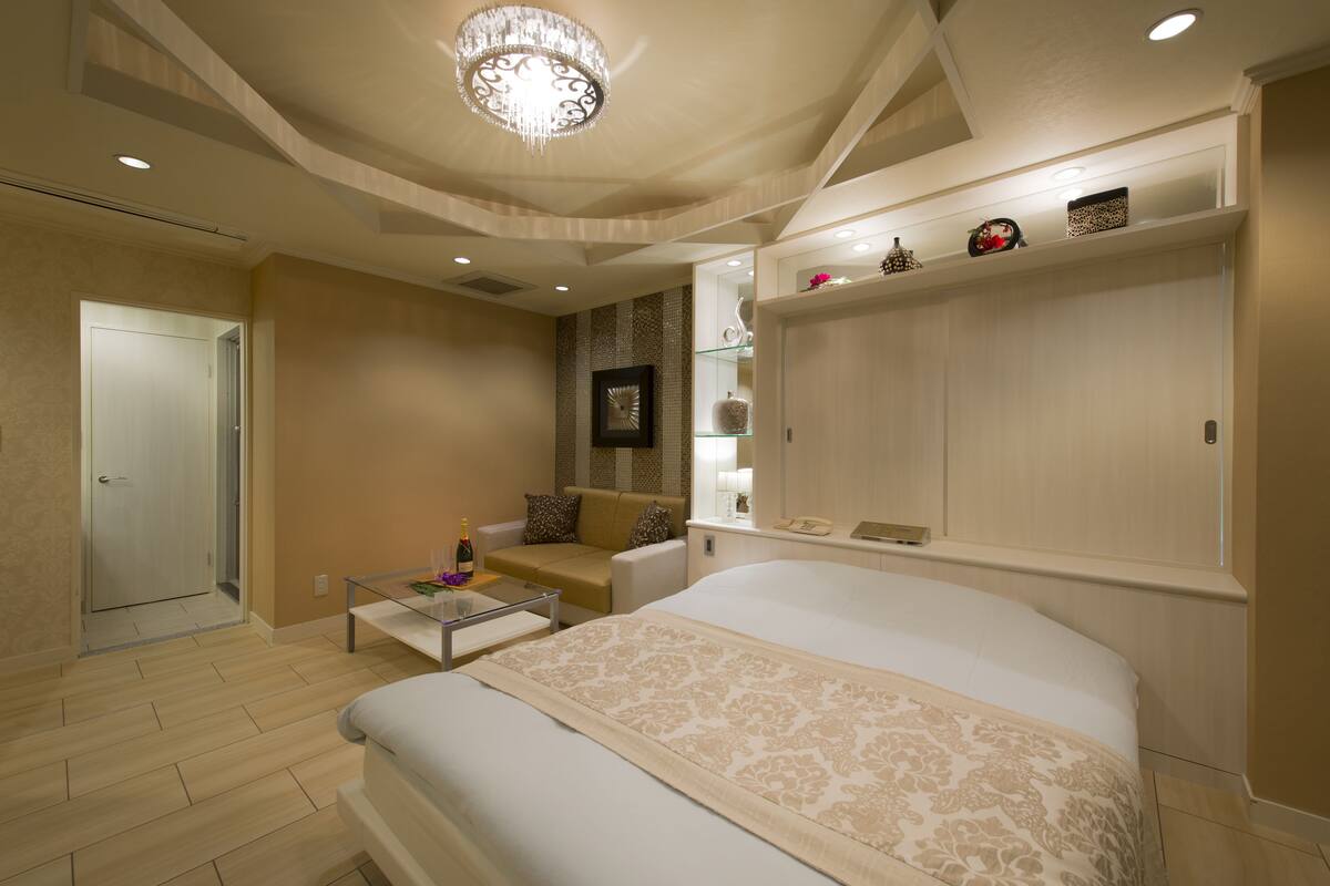 A modern bedroom with a large bed, a glass coffee table, a sofa, and a wardrobe.