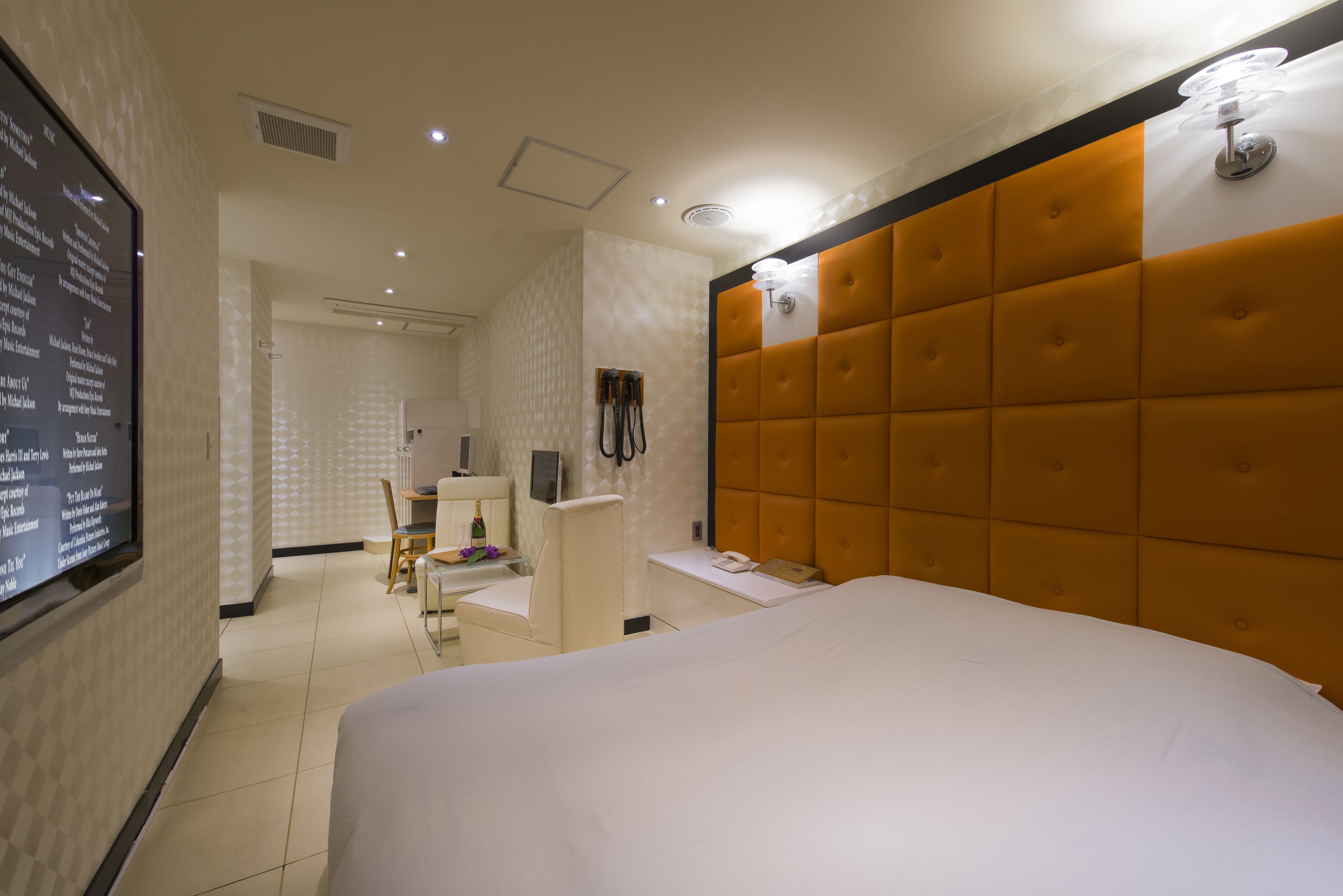 A hotel room with a large bed, a desk with a chair, a television, and a wall-mounted TV.