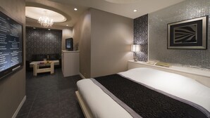 A modern hotel room with a large bed, a vanity with a mirror, and a seating area with a small table and chairs. - Hotel Linden Oji (Tokyo)