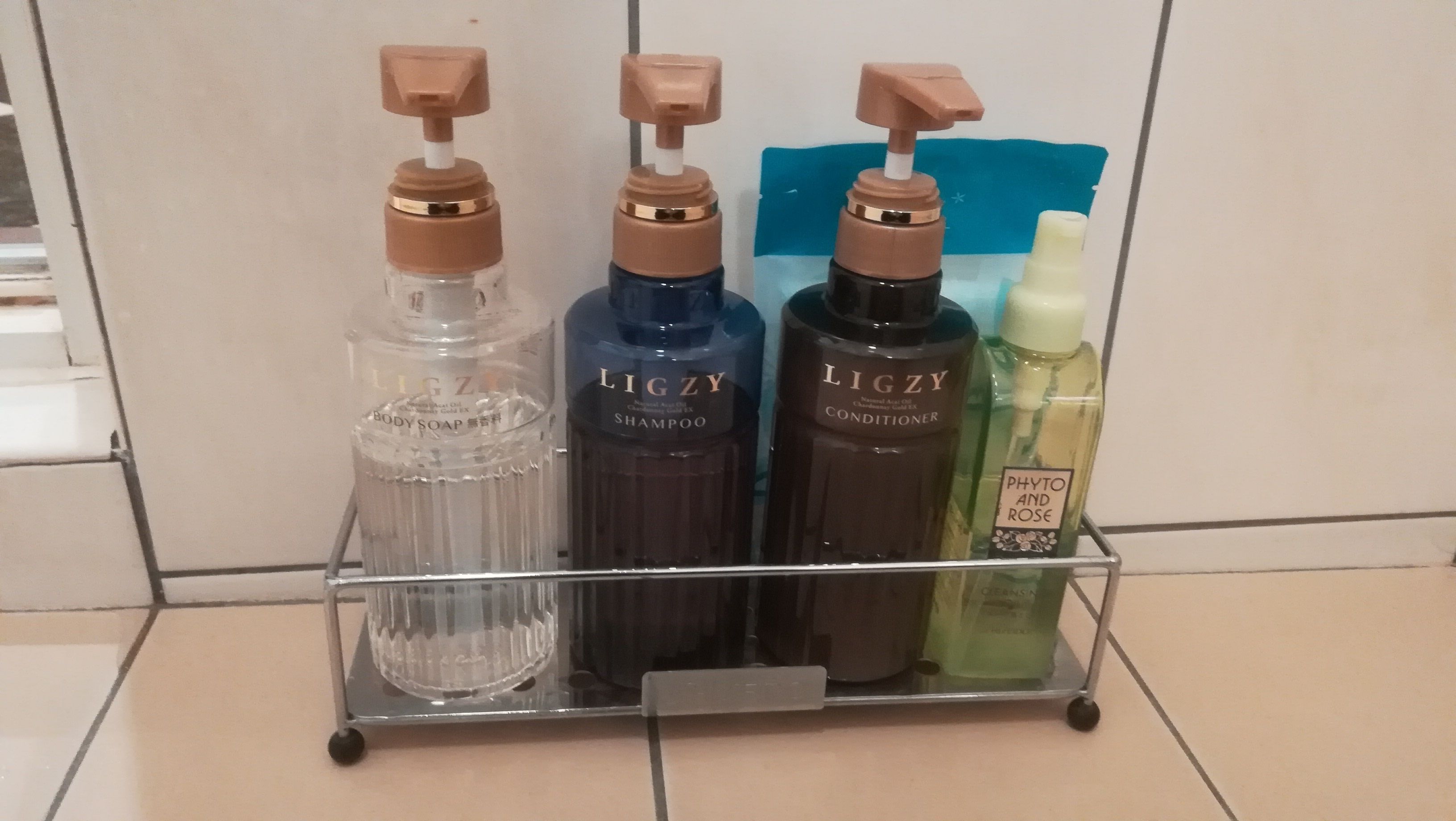 Metallinen hylly, jossa on neljä pulloa vartalotuotteita, ja pulloissa on merkintä ”LIGZY”.