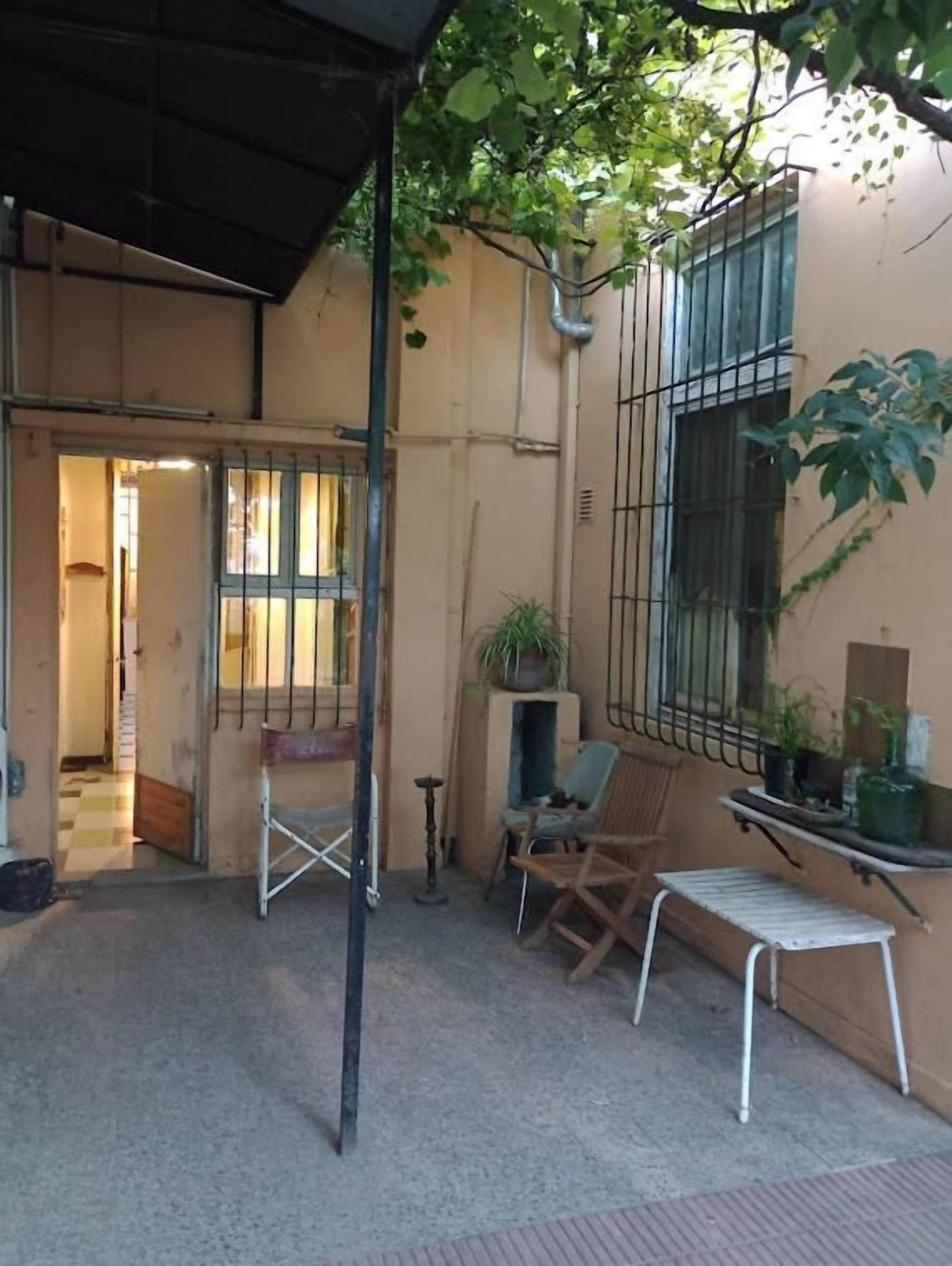 Un pequeño espacio al aire libre con un banco de metal, una silla plegable y una planta en maceta.