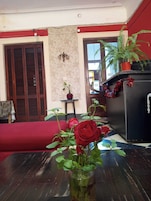 Una sala de estar con un sofá rojo, un aparador negro y un florero con rosas rojas.