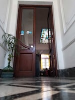 Una puerta de madera que da a un cuarto con piso de baldosas y una planta en maceta.