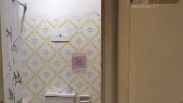 Ein Badezimmer mit Toilette, Handtrockner und Mülleimer.