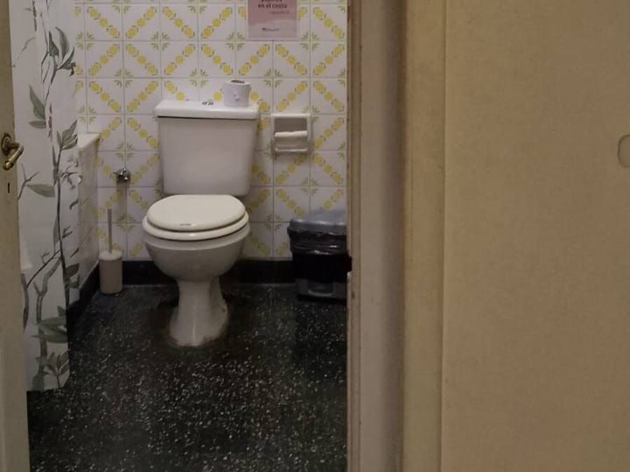 Ein Badezimmer mit Toilette, Handtrockner und Mülleimer.
