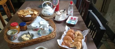 Una mesa dispuesta con té, galletas, croissants y aderezos.
