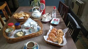 Een gedekte tafel met thee, koekjes, croissants en toevoegingen.