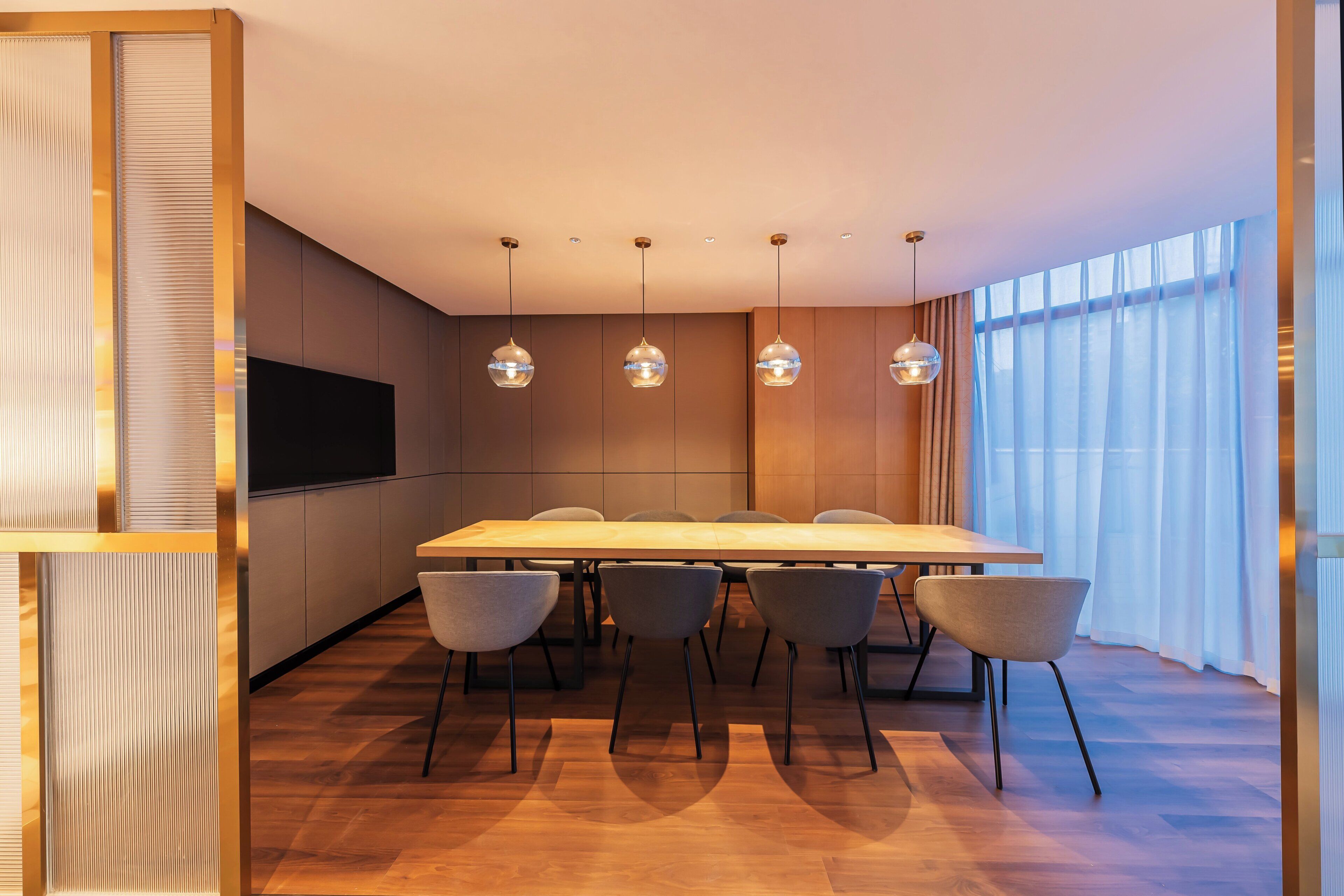 A modern dining room with a long table, six chairs, and pendant lighting.