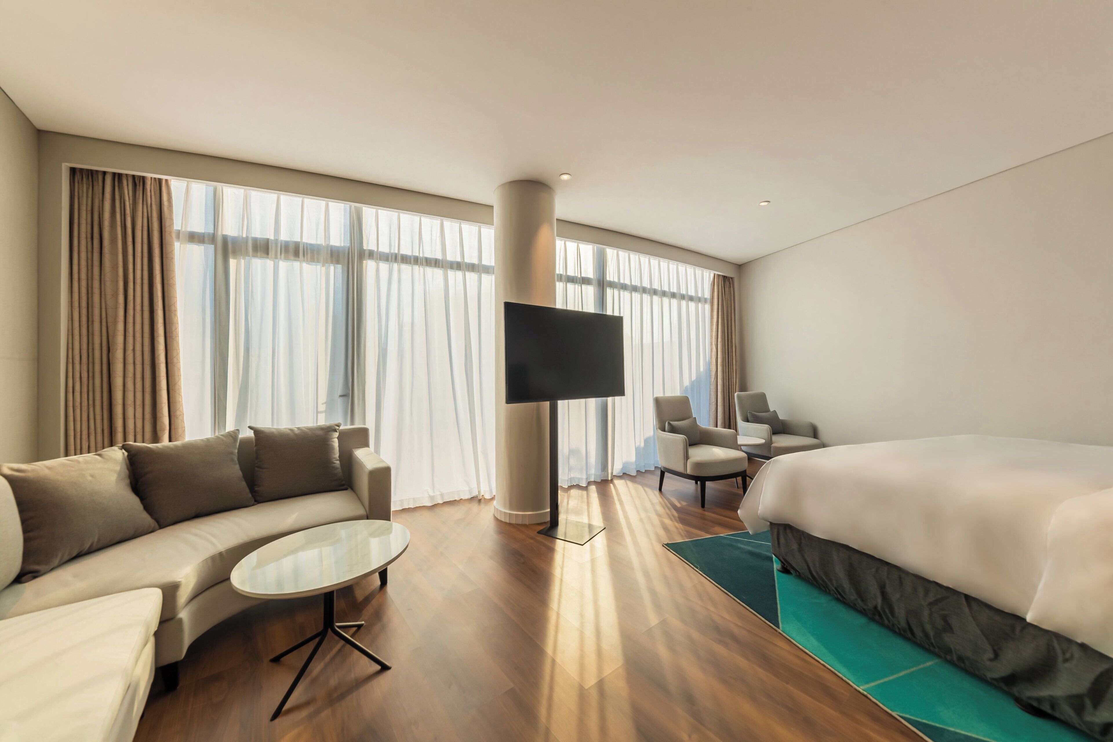 A hotel room with a sofa, a bed, a TV, and a small table.