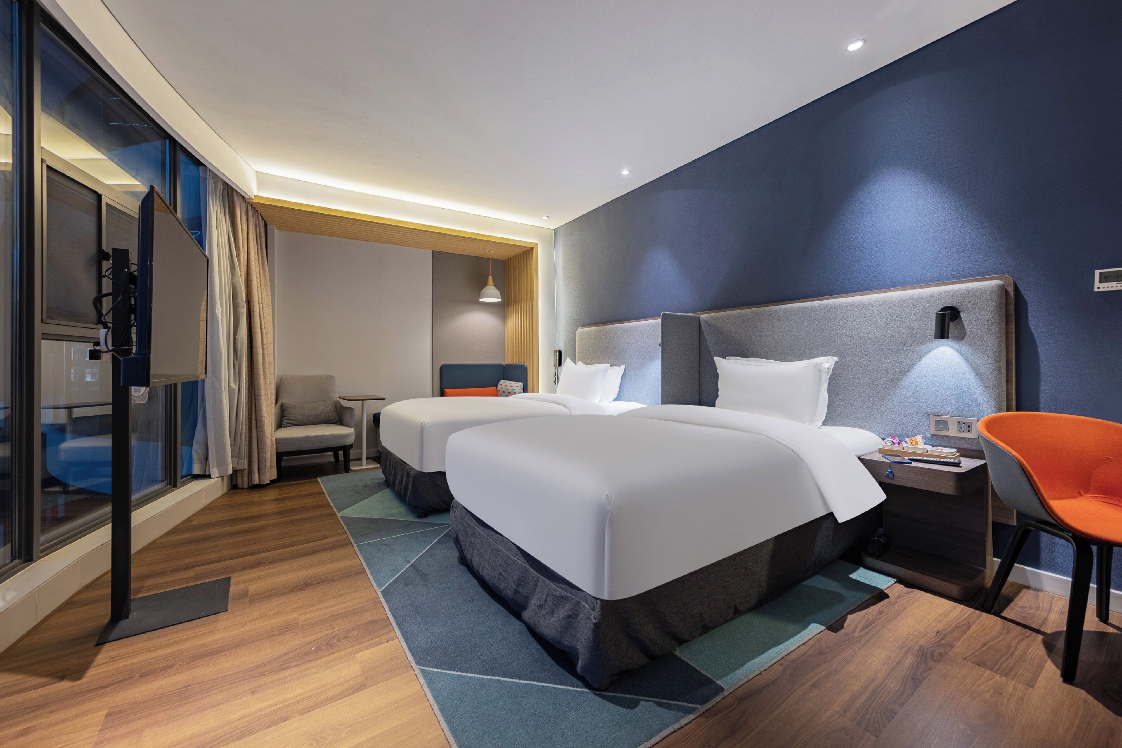 Une chambre d’hôtel avec deux lits, un bureau, une chaise et un téléviseur.