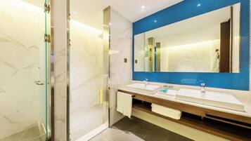 A modern bathroom with two sinks, a large mirror, and a glass shower enclosure.