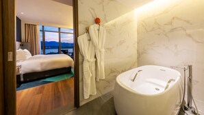A modern hotel room with a large bed, a bathtub, and a view of the mountains. - Holiday Inn Express Yichang Riverside by IHG (Yichang)