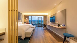 A hotel room with a large bed, a desk with a TV, and a view of the mountains. - Holiday Inn Express Yichang Riverside by IHG (Yichang)