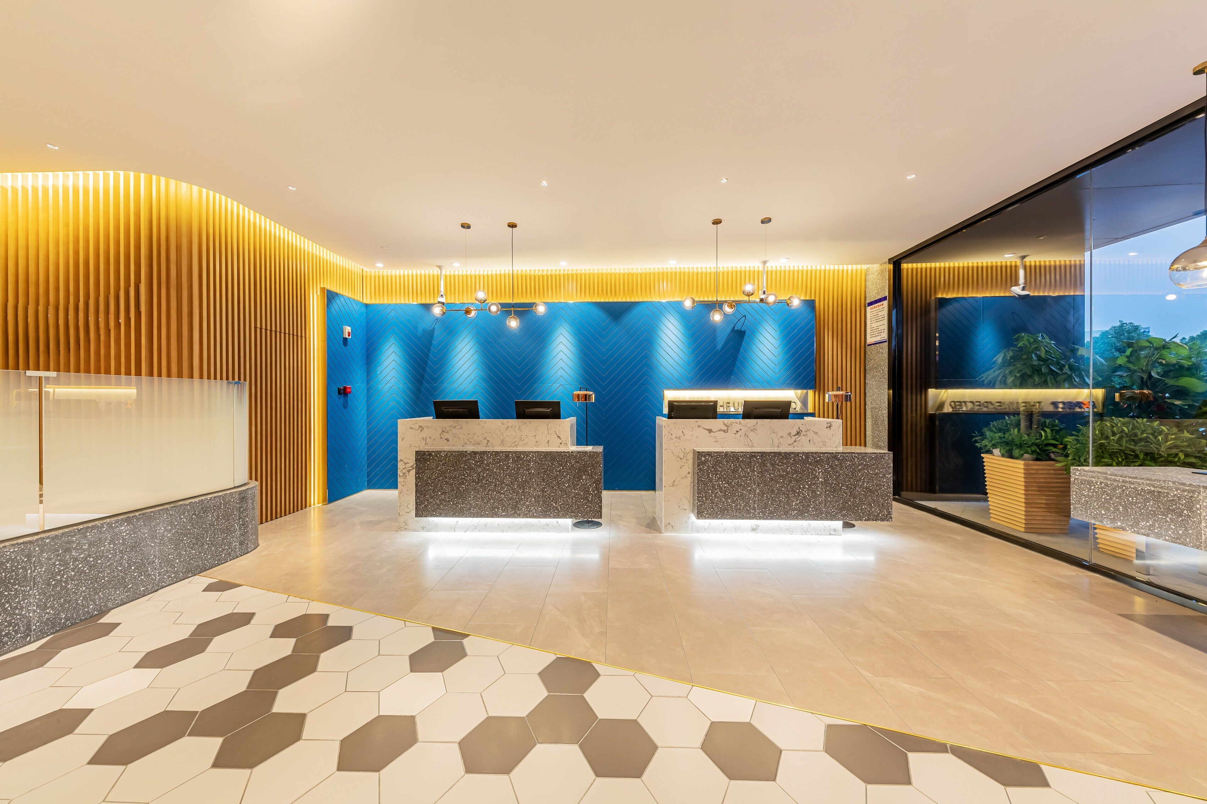 A modern reception area with a blue herringbone wall, a marble reception desk, and a geometric patterned floor.