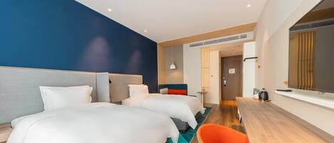 Una habitación de hotel moderna con dos camas, un escritorio de madera y un espejo grande.