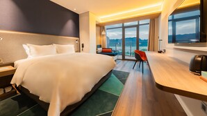 A modern hotel room with a large bed, a desk, a chair, and a view of the mountains. - Holiday Inn Express Yichang Riverside by IHG (Yichang)