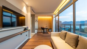 A modern living room with a sofa, a TV mounted on the wall, and a dining area with a table and chairs. - Holiday Inn Express Yichang Riverside by IHG (Yichang)