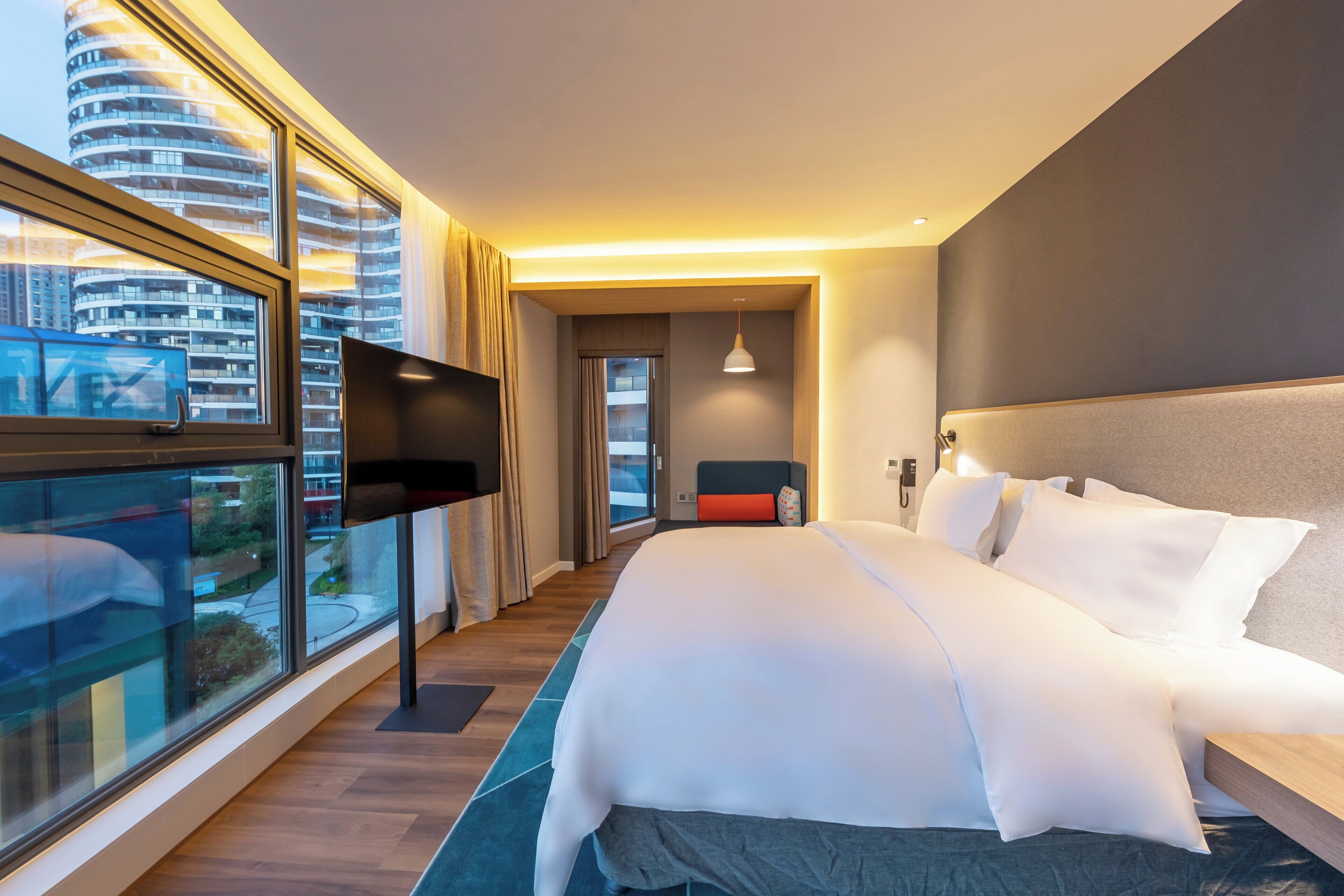 Une chambre d’hôtel moderne dotée d’un grand lit, d’un téléviseur à écran plat et offrant une vue sur la ville.