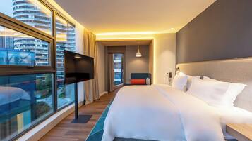 Une chambre d’hôtel moderne dotée d’un grand lit, d’un téléviseur à écran plat et offrant une vue sur la ville.