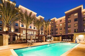 A hotel with a swimming pool, outdoor seating, and palm trees. - Staybridge Suites Irvine-John Wayne Airport by IHG (Irvine)