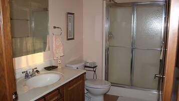 A bathroom with a white sink, a toilet, and a glass shower enclosure.