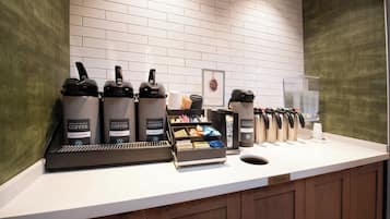 Un angolo caffè con diversi distributori, un cestino e un macinino per il caffè.