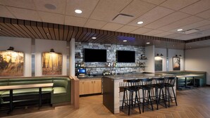 A modern bar area with a stone backsplash, wooden bar stools, and a green cushioned bench.