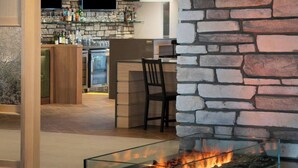 A modern bar area with a stone wall, a flat-screen TV, and a glass-top fire feature.