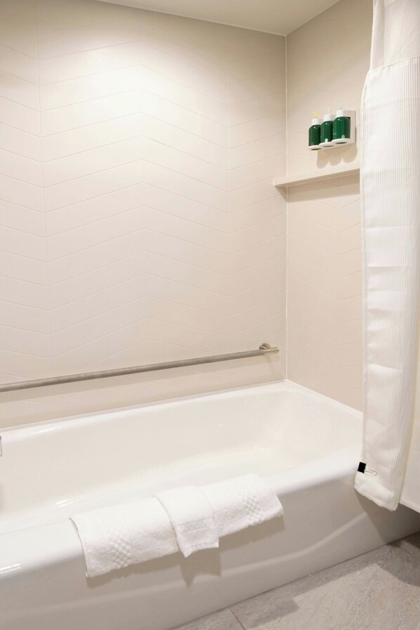 Une salle de bain avec une baignoire blanche, un porte-serviettes et une étagère contenant des articles de toilette.