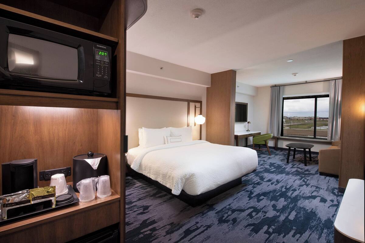 Une chambre d’hôtel équipée d’un lit, d’un bureau, d’une chaise, d’un four à micro-ondes et d’une grande fenêtre.