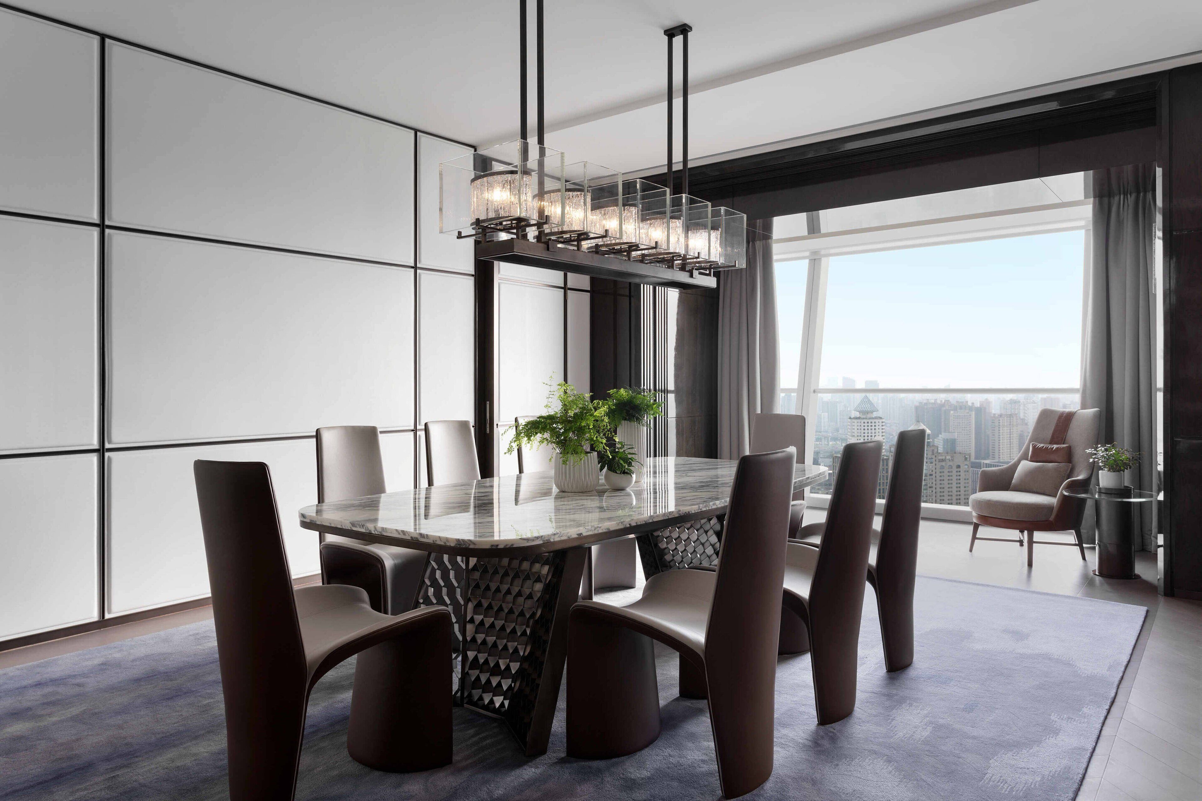 A modern dining area with a glass-top table, six chairs, and a central chandelier.