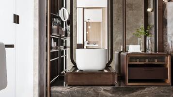A modern bathroom with a large mirror, a white bathtub, and a wooden vanity with a sink.
