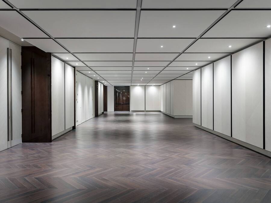 Un hall d’entrée spacieux et moderne, doté d’un parquet à motifs en chevrons et d’un éclairage encastré.