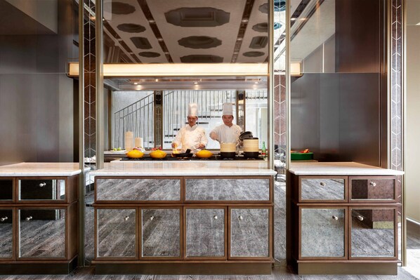 Una cocina moderna con una isla central, dos mostradores laterales y un salpicadero espejado.